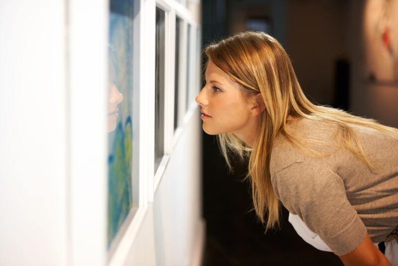Art Galleries in Michigan: A young woman looks closely at an exhibit at an art gallery in West Michigan.