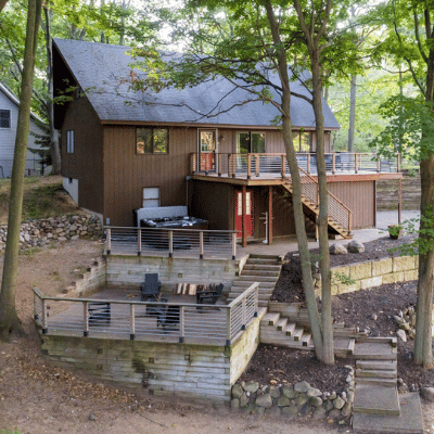 exterior view of loft-style cabin, featuring outdoor fire pit and hot tub with a deck wrapping around the cabin